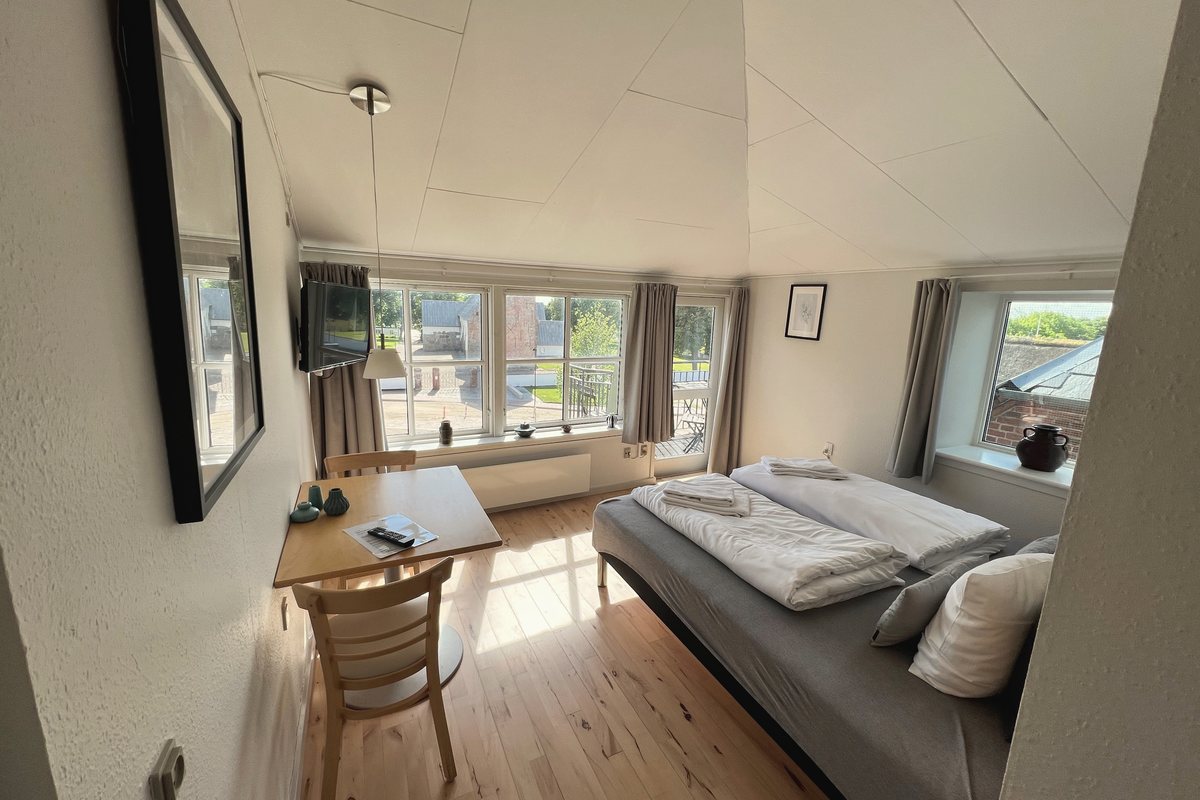Værelse med balkon og lys indretning på Marsk Hotellet